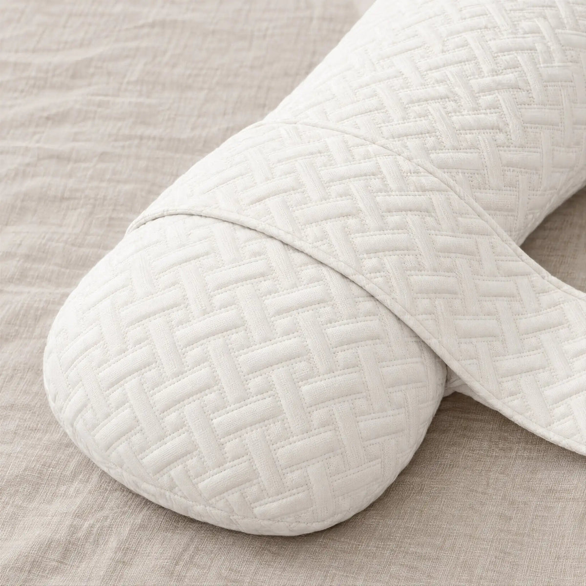 Close-up of the Nurtura body pillow showing its soft ivory quilted cover, textured stitching and fabric connecting strap.