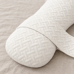 Close-up of the Nurtura body pillow showing its soft ivory quilted cover, textured stitching and fabric connecting strap.